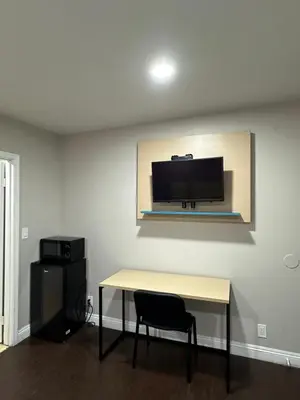 a room with a table and a television on a wall at Sand Piper Motel - Los Angeles in Los Angeles