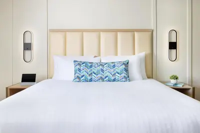 a bedroom with a white bed with a blue pillow at The Anza-a Calabasas Hotel in Calabasas