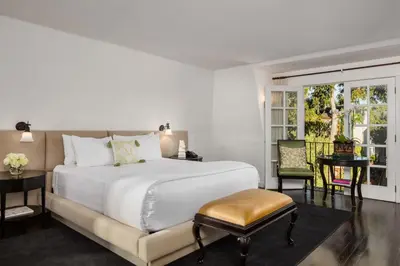a bedroom with a large white bed and a chair at The Charlie West Hollywood in Los Angeles