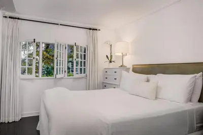 a white bedroom with a large bed with white pillows at The Charlie West Hollywood in Los Angeles
