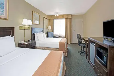 a hotel room with two beds and a flat screen tv at Howard Johnson by Wyndham Torrance in Torrance