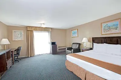 a hotel room with a bed and a desk and chairs at Howard Johnson by Wyndham Torrance in Torrance