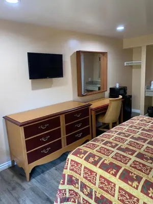 a hotel room with a bed and a desk and a television at Budget Inn Motel in San Gabriel