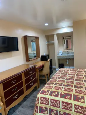 a hotel room with a bed and a desk and a television at Budget Inn Motel in San Gabriel