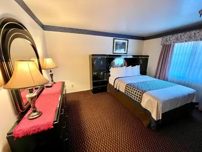 a hotel room with a bed and a lamp on a red bench at Oakridge Inn in Oak View