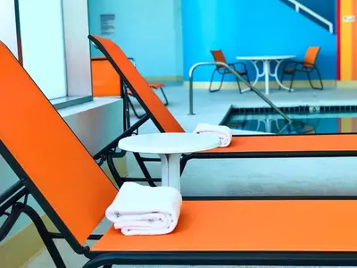 two orange chairs and a table with towels on them at Hotel Huntington Beach in Huntington Beach