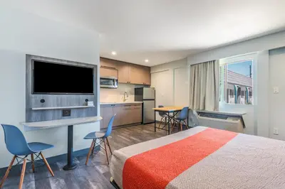 a hotel room with a bed and a flat screen tv at Solo Motel Broadway in Los Angeles