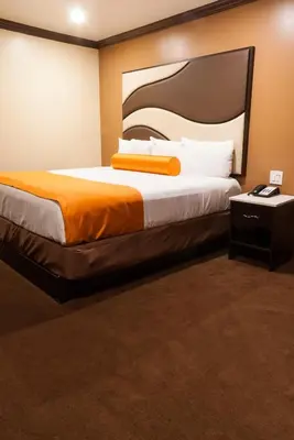 a bedroom with a large bed with an orange blanket at Redondo Pier Inn in Redondo Beach