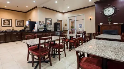 a restaurant with tables and chairs and a clock on the wall at Best Western Route 66 Glendora Inn in Glendora