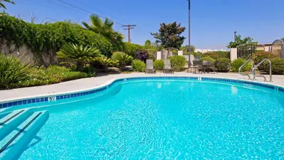 a large blue swimming pool with chairs and trees at Best Western Route 66 Glendora Inn in Glendora