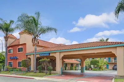 a hotel front of a building with a parking lot at Travelodge by Wyndham Lynwood in Lynwood