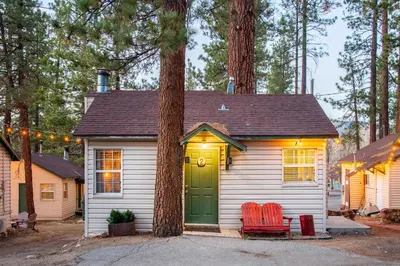 a small house with a green door and two chairs at Lakewood Cabins in Big Bear Lake