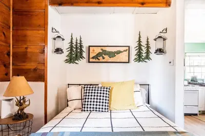 a bedroom with a bed and pine trees on the wall at Lakewood Cabins in Big Bear Lake