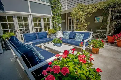 a patio with blue couches and red flowers and plants at Inn at Playa del Rey in Los Angeles