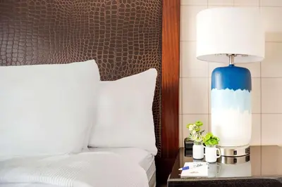 a bed with a blue lamp on a table next to it at Hotel Lulu, BW Premier Collection in Anaheim