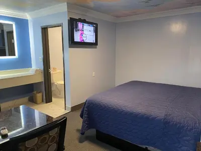a bedroom with a bed and a tv on the wall at Golden West Manor Motel in Los Angeles