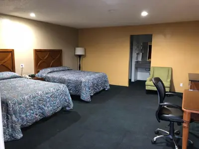 a hotel room with two beds and a chair at Los Angeles Inn & Suites - LAX in Los Angeles