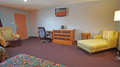 a hotel room with a bed and a desk and chairs at Los Angeles Inn & Suites - LAX in Los Angeles