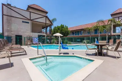 a swimming pool with a table and chairs next to a building at Howard Johnson by Wyndham Norco in Norco