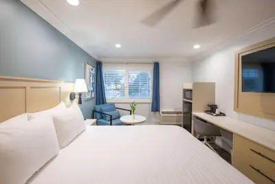 a bedroom with a large white bed and a desk at Ramada by Wyndham Redondo Beach in Redondo Beach