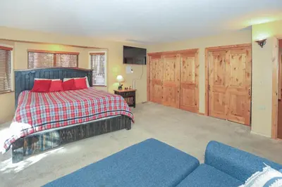 a bedroom with a bed with red pillows and a couch at The Lodge at Snow Summit Home in Big Bear Lake