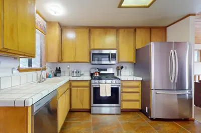 a kitchen with wooden cabinets and a stainless steel refrigerator at Victoria Court Vacation in Lake Arrowhead