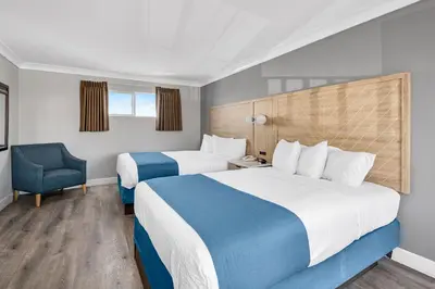 a hotel room with two beds and a chair at Vagabond Inn Whittier in Whittier