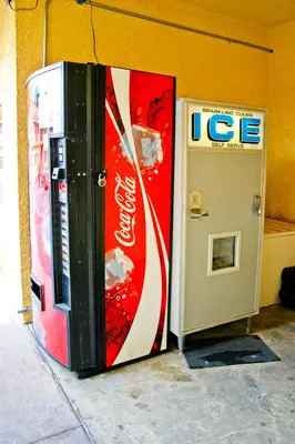 a cocacola soda machine next to a ice box at Diamond Inn in Inglewood