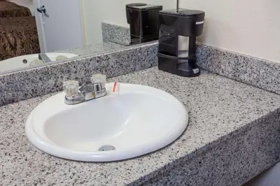 a bathroom counter with a white sink and a coffee maker at Days Inn by Wyndham Anaheim West in Anaheim