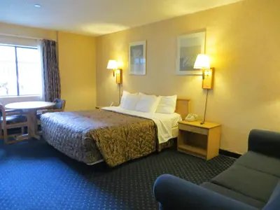a hotel room with a bed and a chair and a table at Days Inn by Wyndham Anaheim West in Anaheim