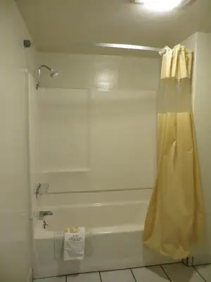 a bathroom with a tub and a shower with a shower curtain at Days Inn by Wyndham Anaheim West in Anaheim