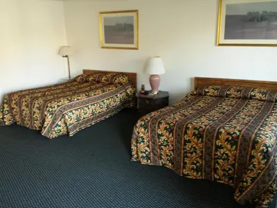 a hotel room with two beds and a lamp on a table at New Kansan Motel in Rancho Cucamonga