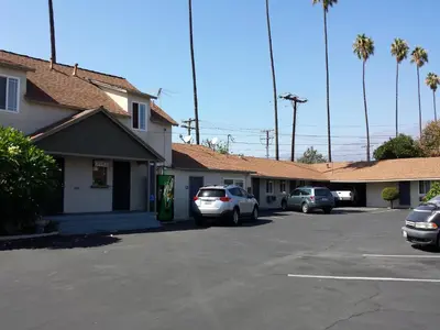 a parking lot with cars parked in front of a building at New Kansan Motel in Rancho Cucamonga