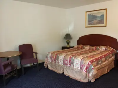 a bedroom with a bed and a table and a chair at New Kansan Motel in Rancho Cucamonga