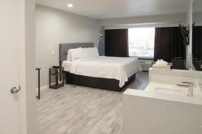 a hotel room with a bed and a sink at Capri Suites Anaheim in Anaheim