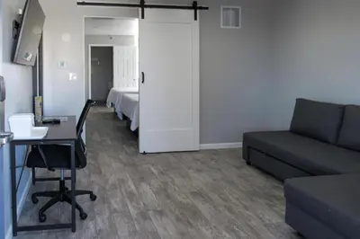 a living room with a couch and a table and a bed at Capri Suites Anaheim in Anaheim