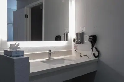 a bathroom with a sink with a mirror and a phone at Capri Suites Anaheim in Anaheim