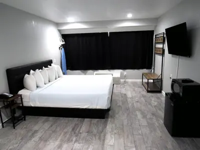 a hotel room with a bed and a flat screen tv at Capri Suites Anaheim in Anaheim