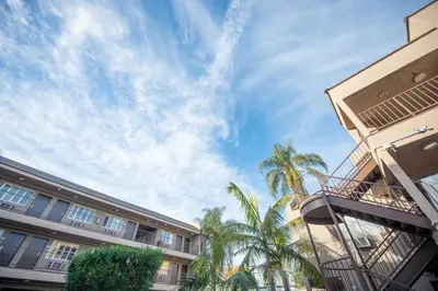 a building with palm trees in front of a blue sky at Casa Bella Inn- Huntington Park in Huntington Park