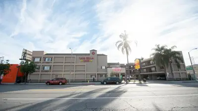 an empty street with cars parked in front of a building at Casa Bella Inn- Huntington Park in Huntington Park