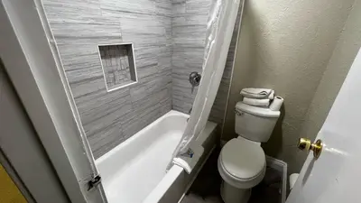 a small bathroom with a toilet and a bath tub at New American Inn & Suites in Anaheim