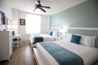 a hotel room with two beds and a ceiling fan at Hotel Carmel Santa Monica in Los Angeles