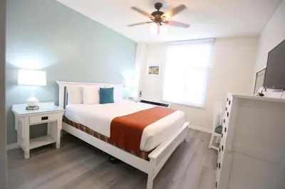 a white bedroom with a bed and a ceiling fan at Hotel Carmel Santa Monica in Los Angeles