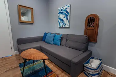 a living room with a gray couch and a stool at Broadlind Hotel in Long Beach