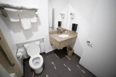 a white bathroom with a toilet and a sink at Mid City Inn & Suites Pico Rivera in Pico Rivera