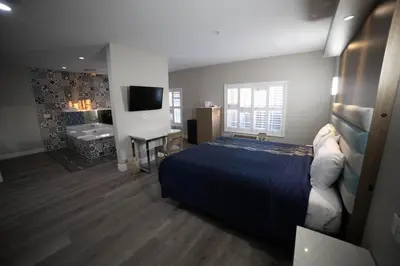 a bedroom with a bed and a bathroom with a tub at Mid City Inn & Suites Pico Rivera in Pico Rivera