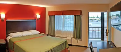 a hotel room with a bed and a balcony at Epic Hotel in Pico Rivera