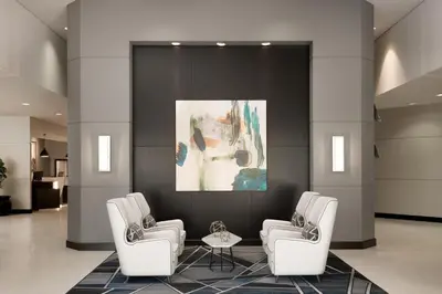 a lobby with three white chairs and a painting at Sheraton Cerritos in Buena Park