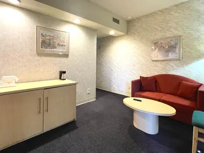 a waiting room with a red couch and a table at Park Suites Hotel in South El Monte