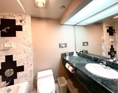 a bathroom with a sink and a toilet and a mirror at Park Suites Hotel in South El Monte